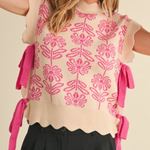 Woman wearing a ribbed scallop floral sweater vest with pink tassels on a beige background